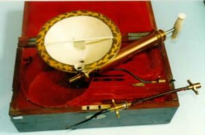 A detailed image of the Ferguson blood transfusion set, a cream bowl with gold patterned detailing is in the middle, with accompanying gold implements for withdrawing blood, all seated within a hinge top wooden box with deep red velvet lining.