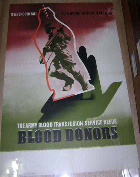The poster depicts a soldier inside a glass blood flask, as polythene blood bags were not used in Britain until the 1970s. The red and green colour scheme is indicative of the importance of blood transfusion and saving lives. The poster states: ‘If he should fall, is your blood there to save him? The Army Blood Transfusion Service Needs Blood Donors’.